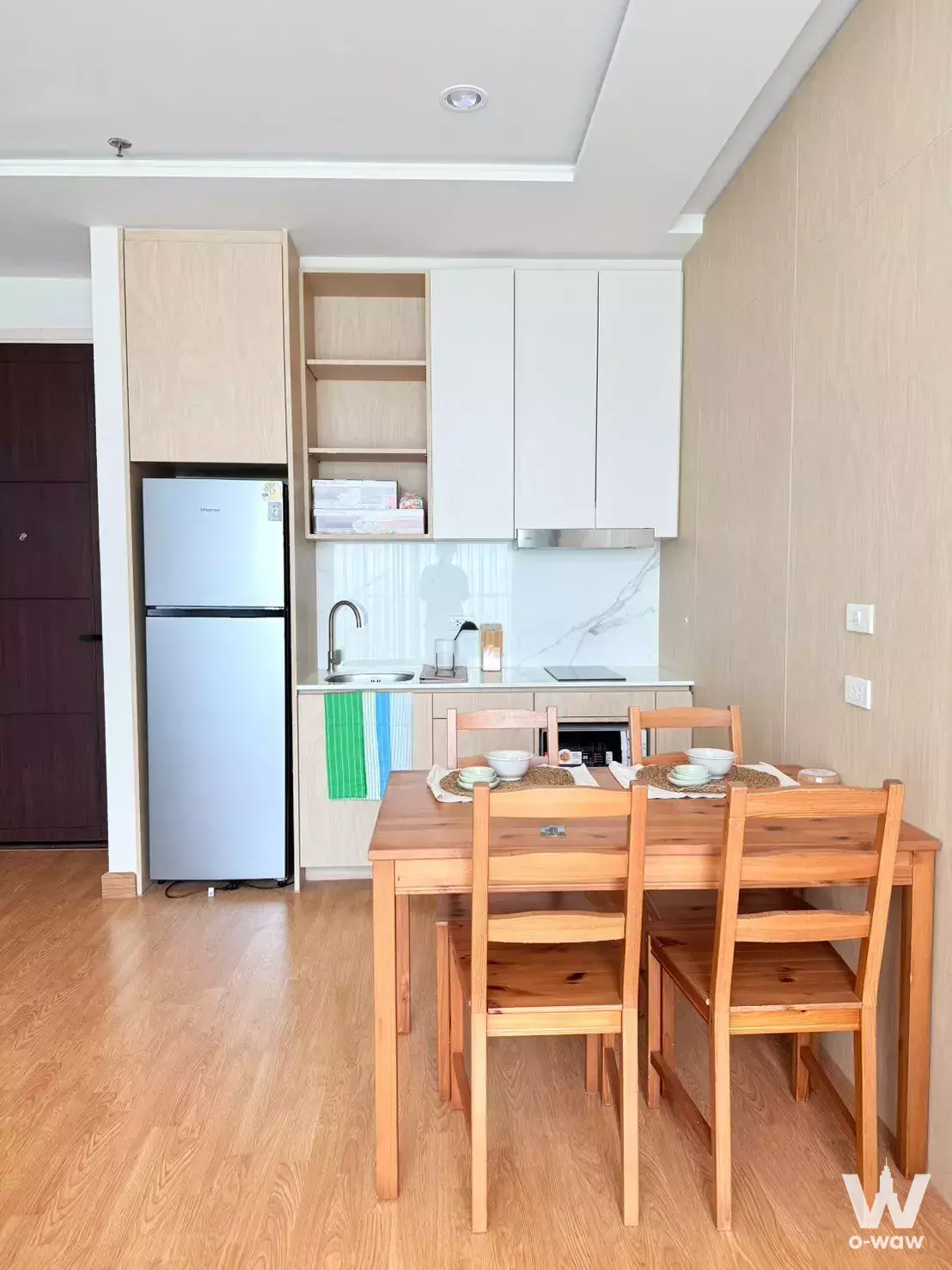 Compact kitchen and dining area in 2-bed Q House Sukhumvit 79 condo featuring white cabinets, wood accents, and dining set
