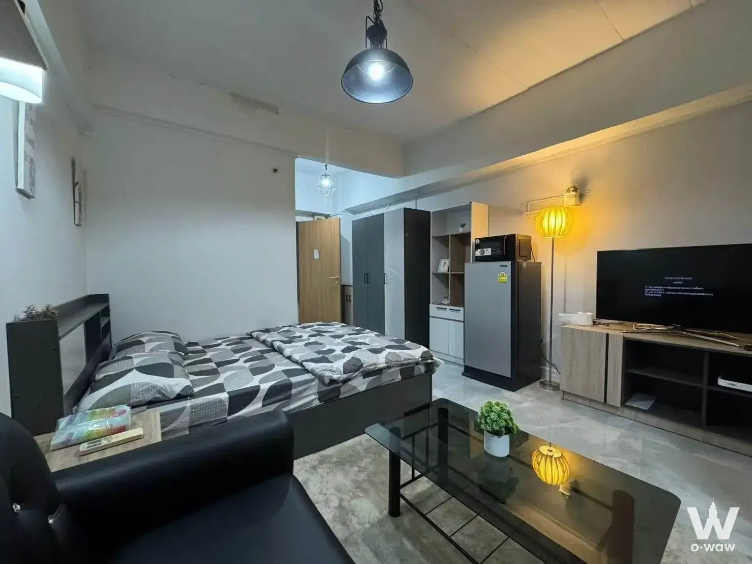 Modern 1-bed condo bedroom in Sawasdee Bangkok with dark bed frame and marble-effect tile flooring