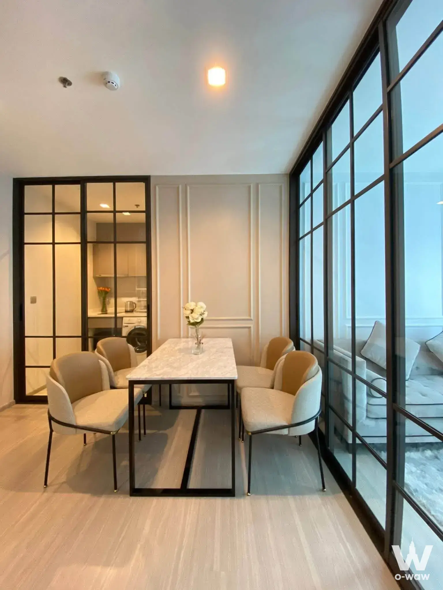 The dining area has a marble table, four chairs and a glass partition in a furnished 1-bed Life Asoke Rama 9 condo