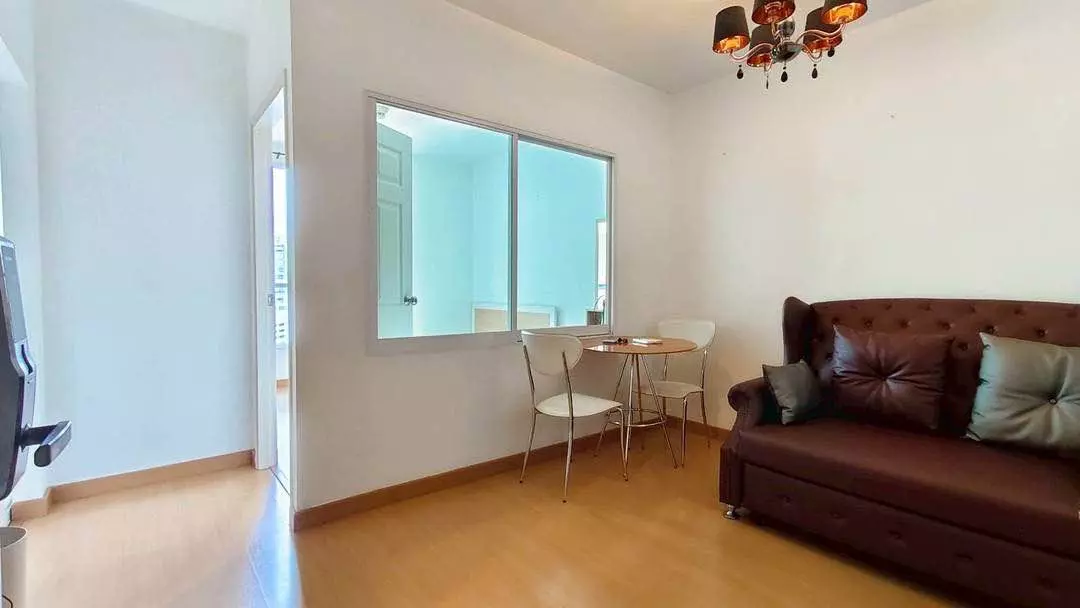 Living area in Life @ Sukhumvit 65 condo with leather sofa, round dining table, and amber chandelier