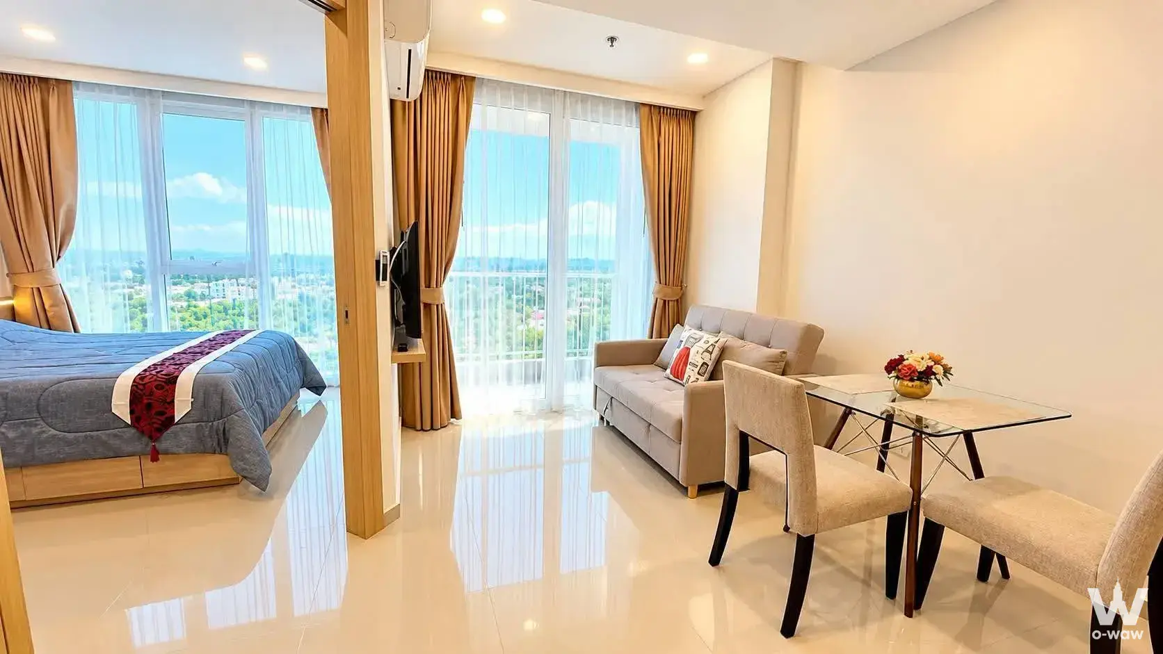 Bright 1-bed condo studio with city skyline view, grey sofa, and glass dining table in City Garden Pattaya