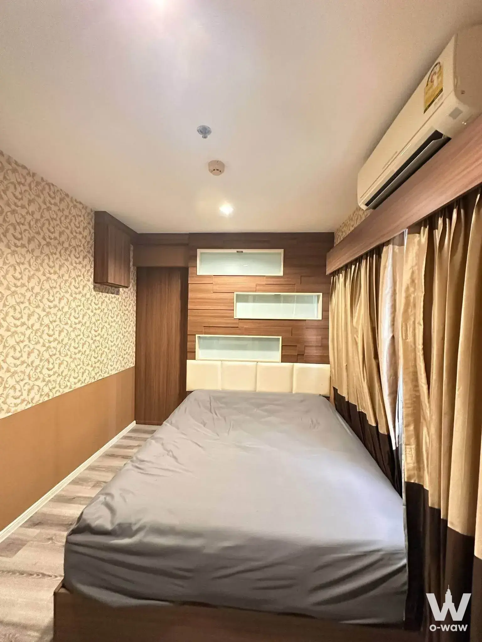 Bedroom of a 2-bed rental condo at Lumpini Mega City Bang Na with queen bed and frosted glass shelves