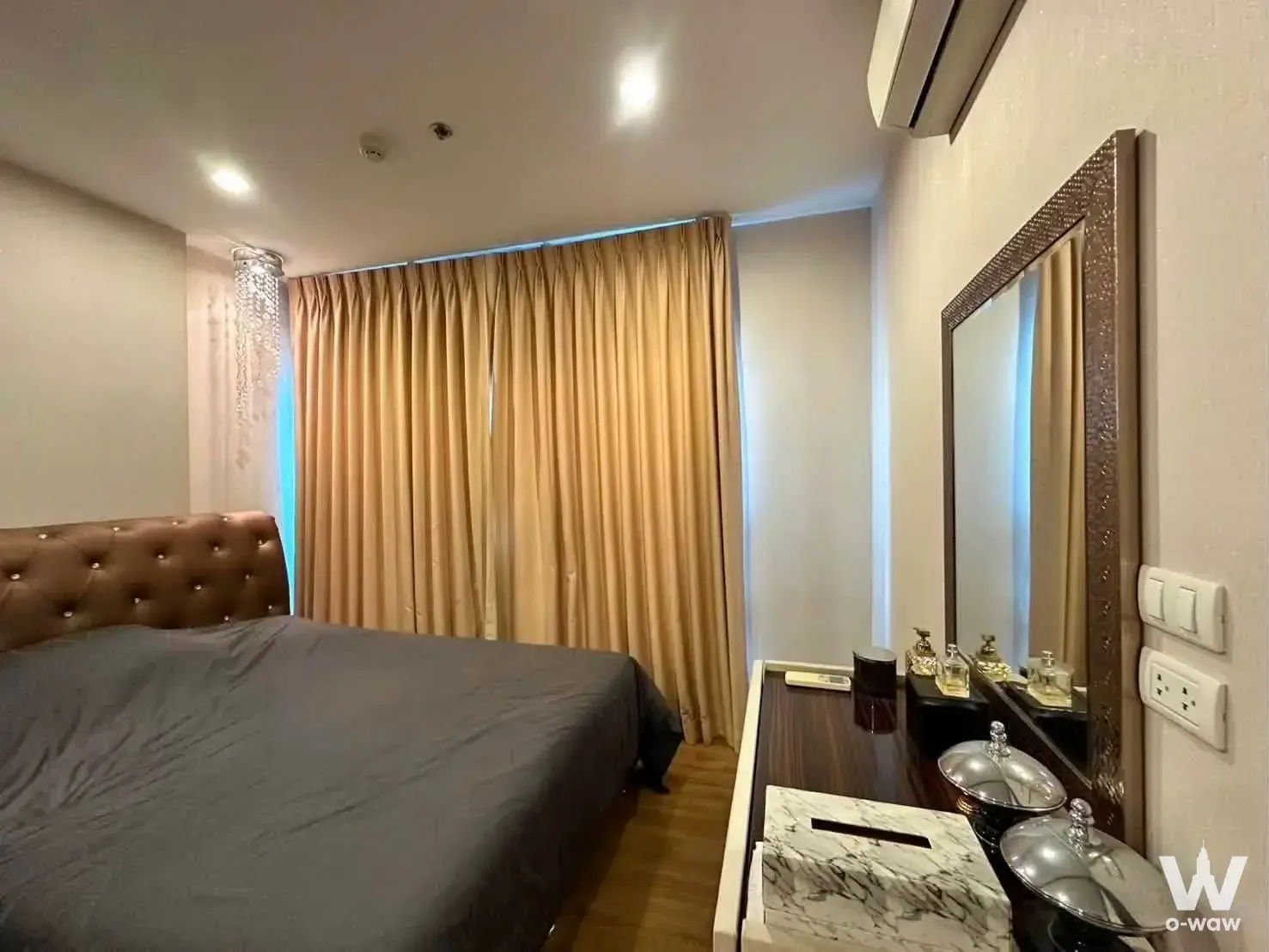 Bedroom in The Tree Rio Bang-Aor Station featuring a tufted leather headboard and gold satin curtains