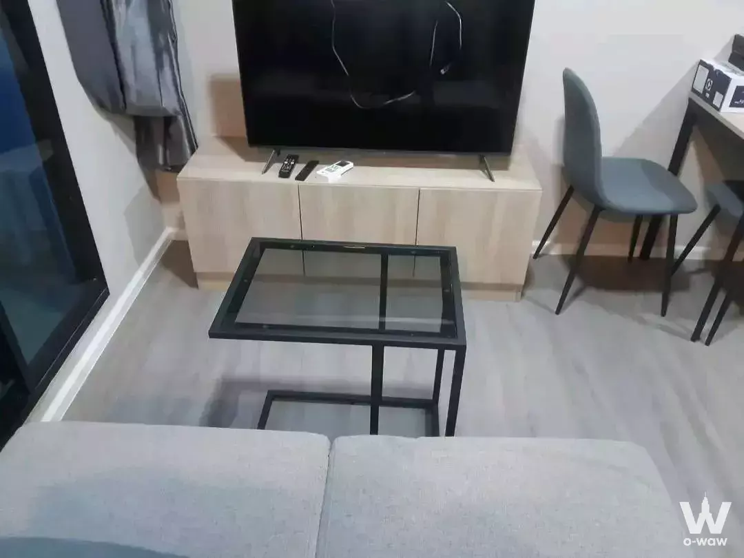 Compact living area in dcondo Campus Hideaway 1-bed condo with grey sofa, black coffee table, and light wood flooring