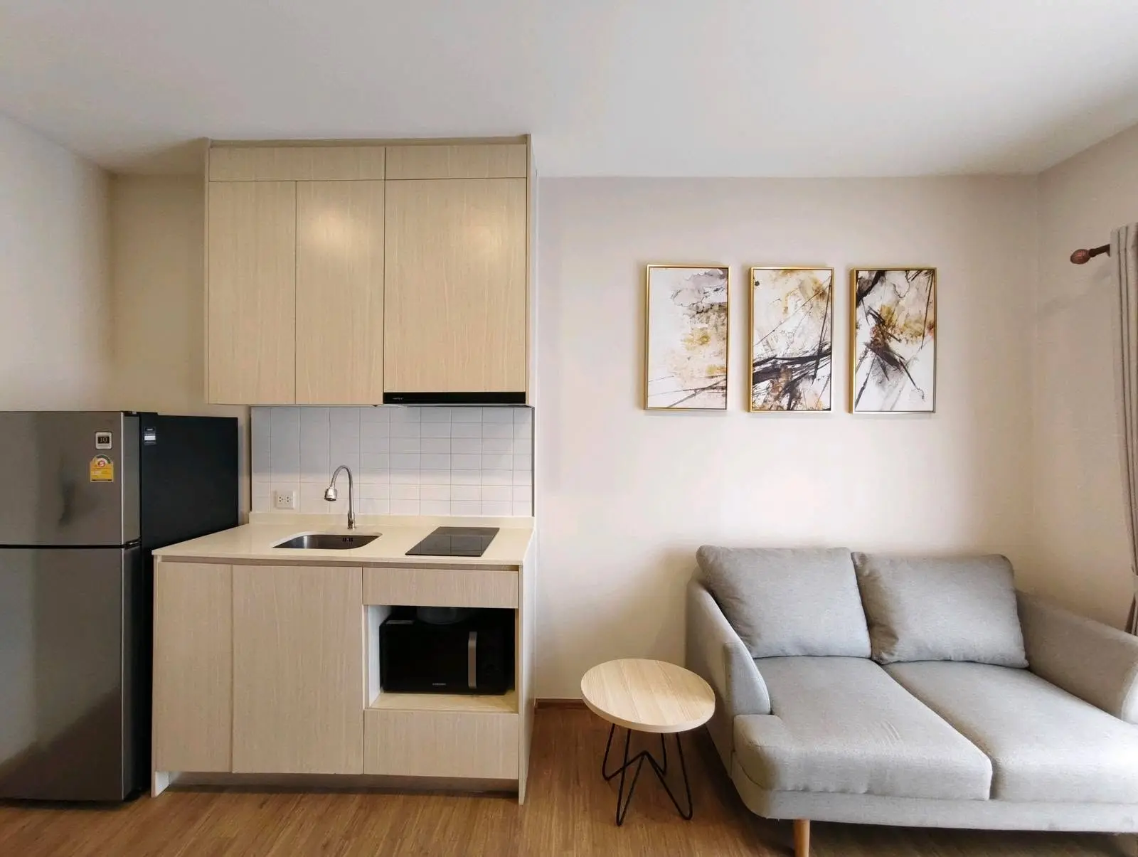 Modern studio kitchen in Metris Rama 9-Ramkumhang with light wood cabinets, white countertops, and minimalist decor