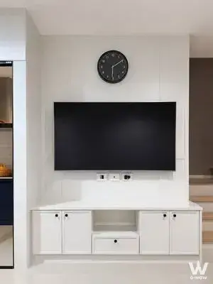 Living room entertainment wall in Nirvana Define Rama 9 townhouse featuring mounted TV, floating console, and stairs