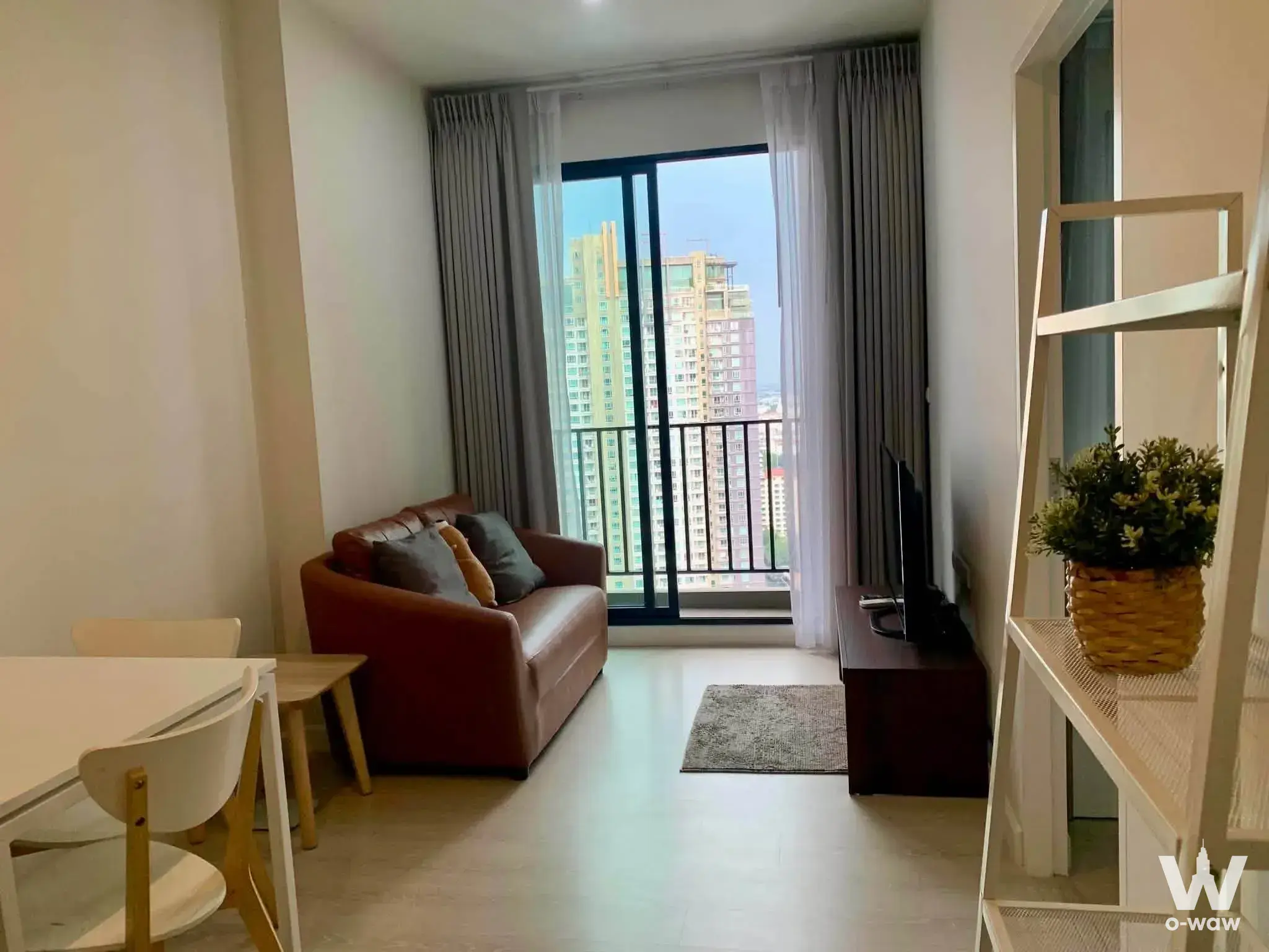 Furnished living room at Nich Pride condo with sofa and balcony access
