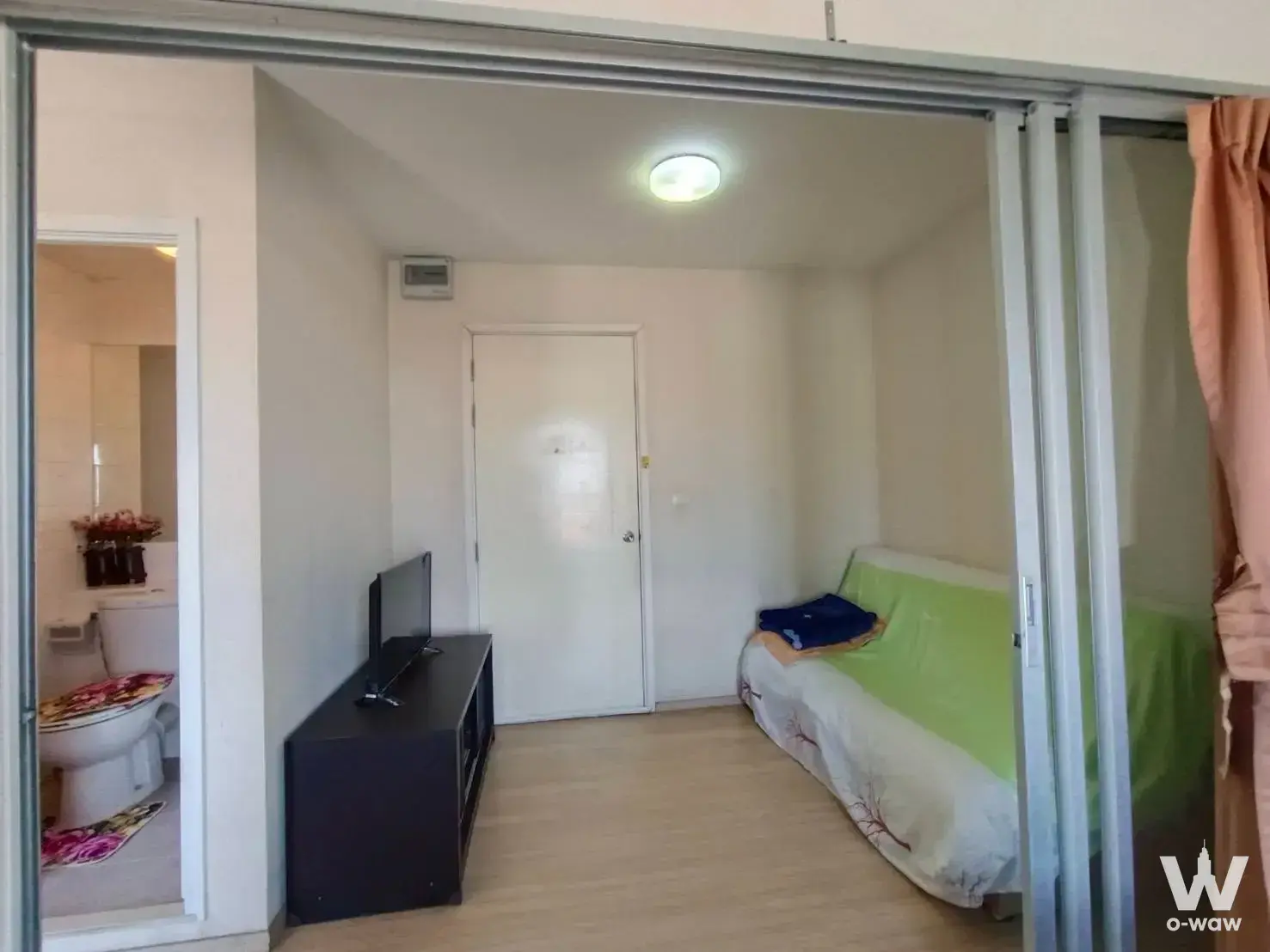 Compact bedroom with lime green bedding and open bathroom in Plum Condo Bang Yai