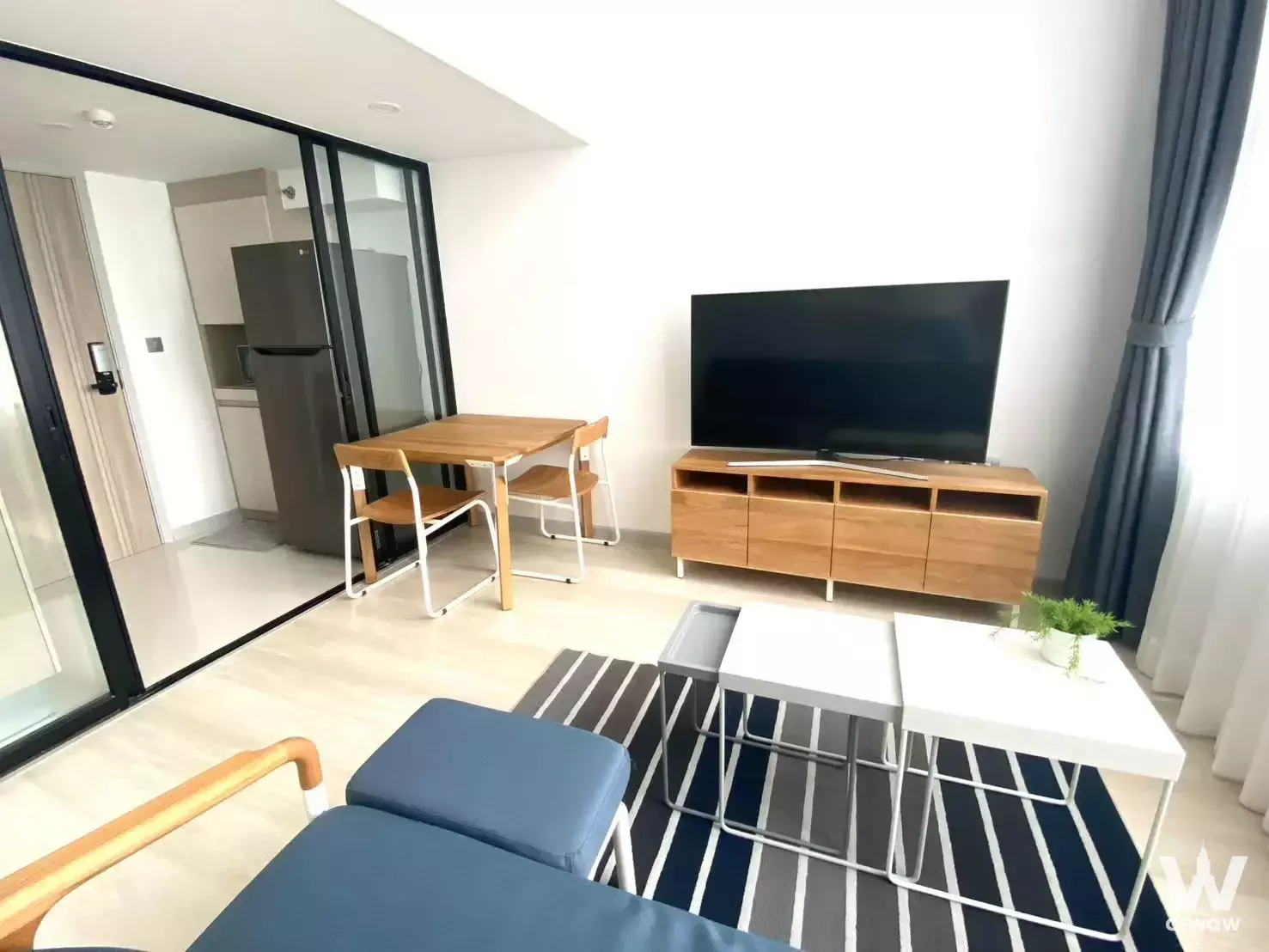 Blue sofa and wood dining table in KnightsBridge Prime Sathon 1-bed condo living area
