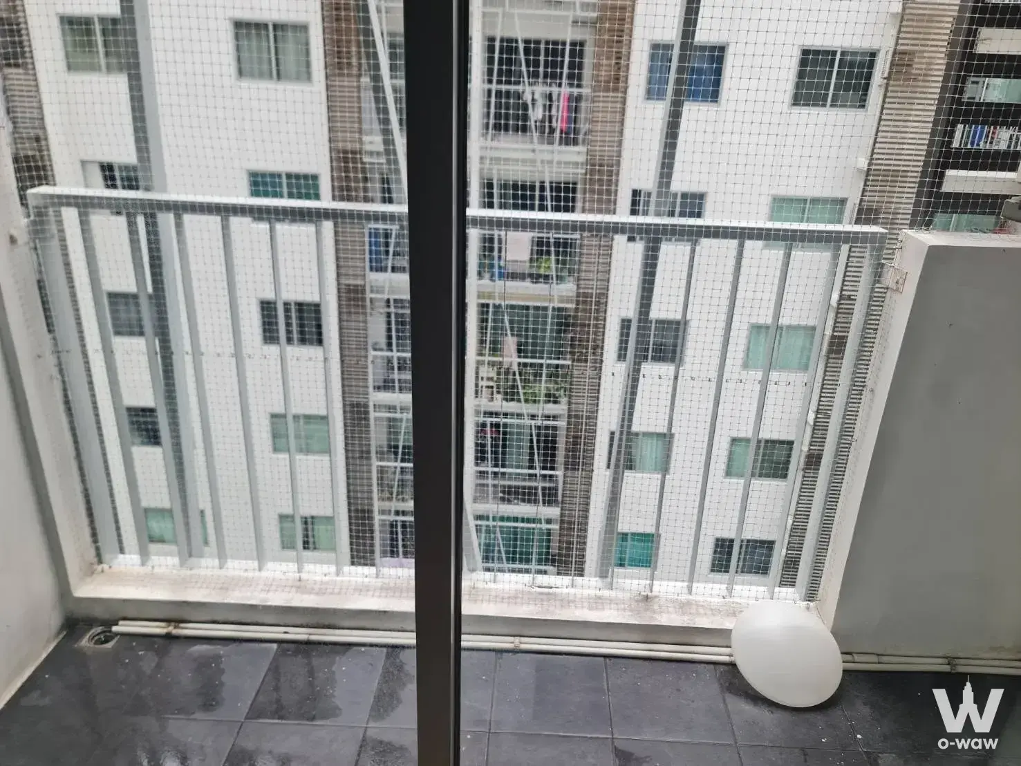 Balcony of a 1-bed condo for rent at Aspire Asoke-Ratchada with grey tiles, safety railing, and adjacent high-rise buildings