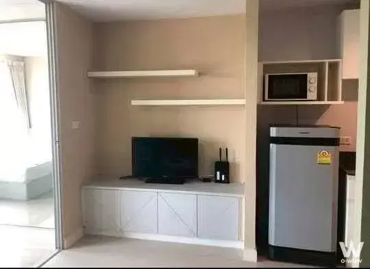 Compact living space in Swift Condo featuring white media console, built-in kitchenette niche, and sliding door