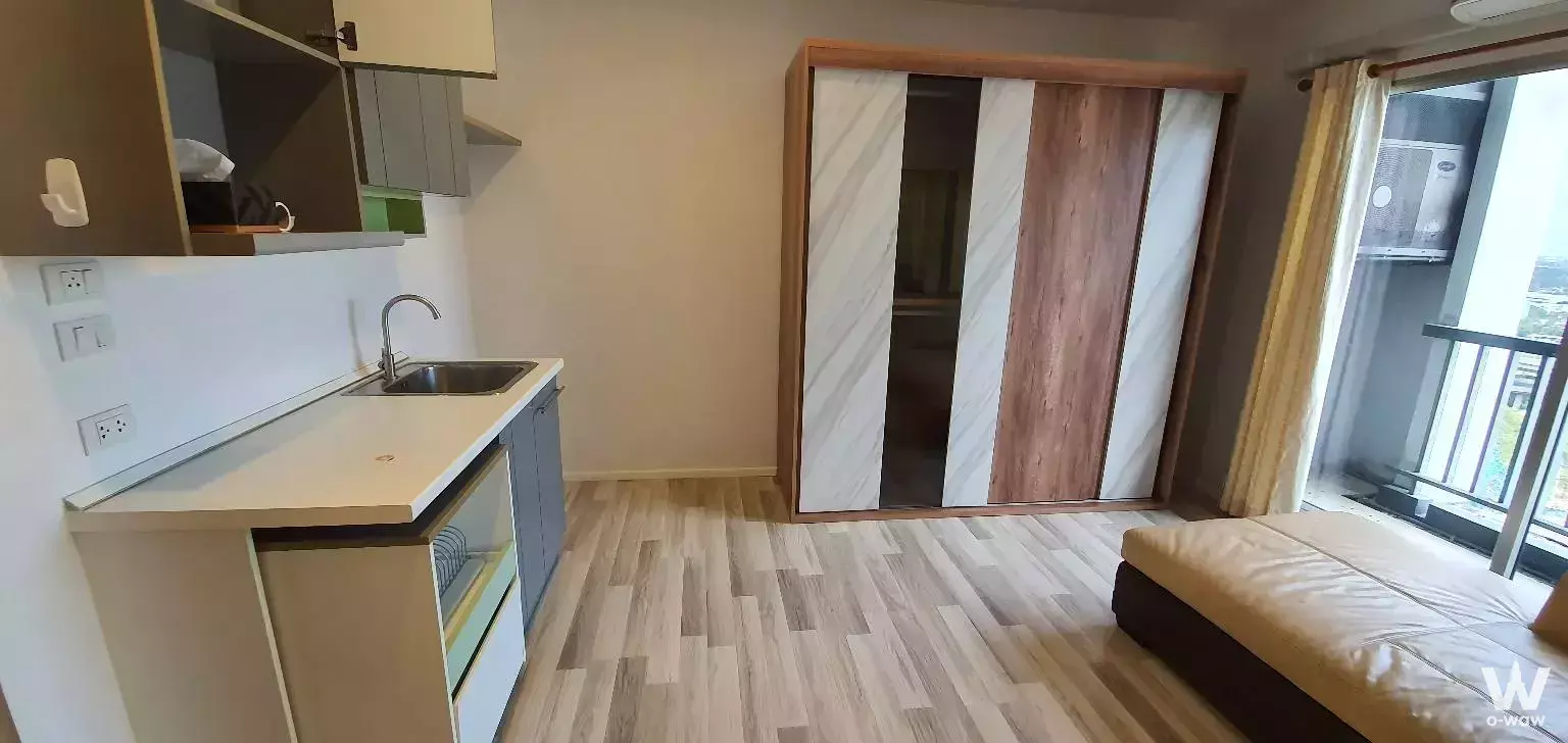 Studio bedroom in The Key Cheangwattana with integrated kitchenette, marble-effect wardrobe, and balcony door