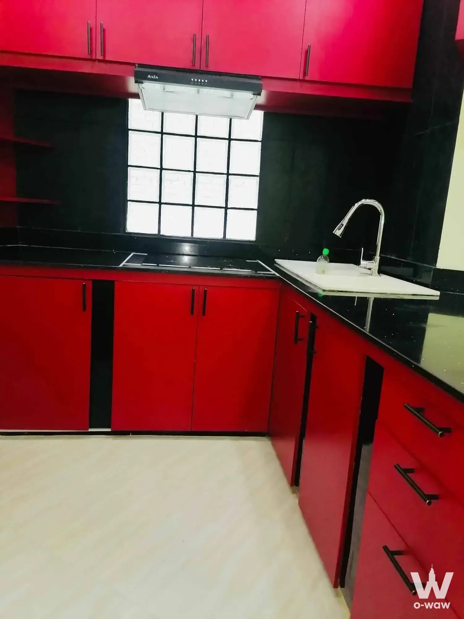 Modern kitchen in a Park24 rental with glossy red cabinetry, black granite countertops, and a built-in gas cooktop