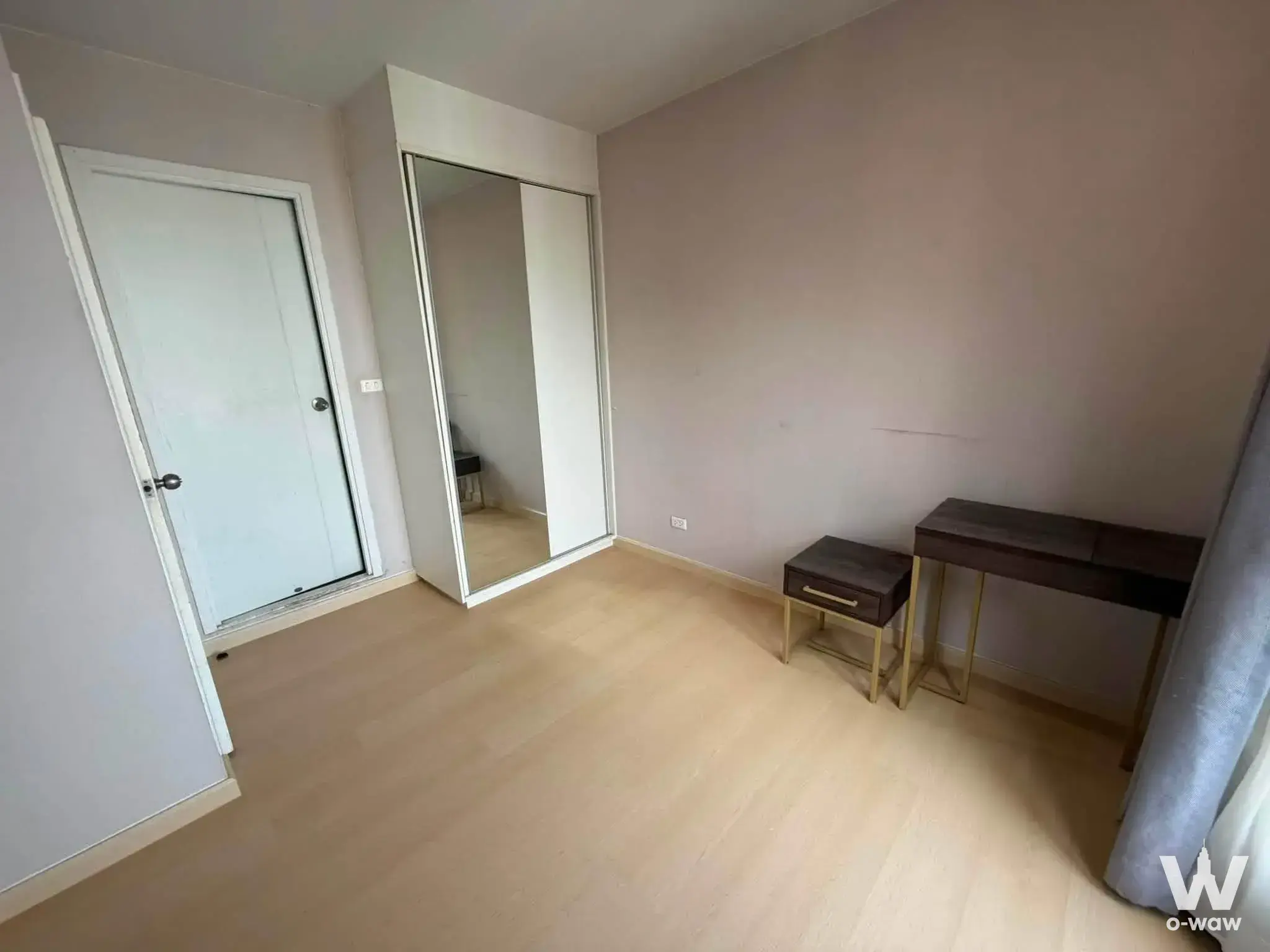 Empty bedroom with built-in wardrobe and gold-legged console table at Plum Condo Pinklao