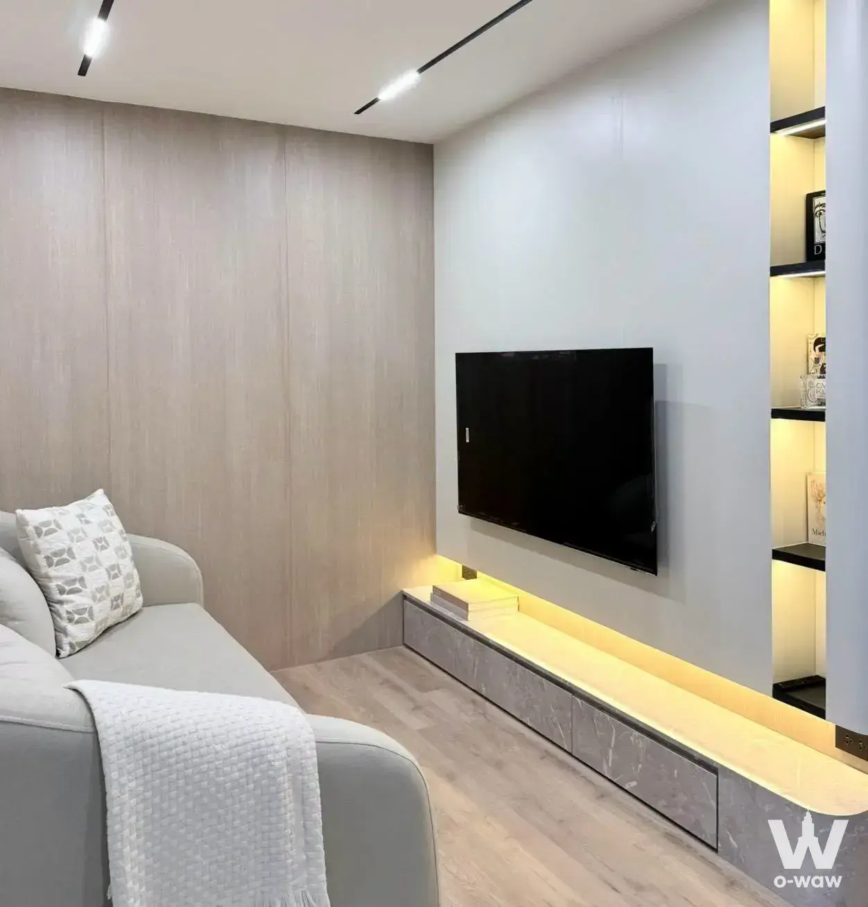 1-bed condo for sale in Rawee Waree Condominium living room with minimalist sofa, floating media console, and warm LED