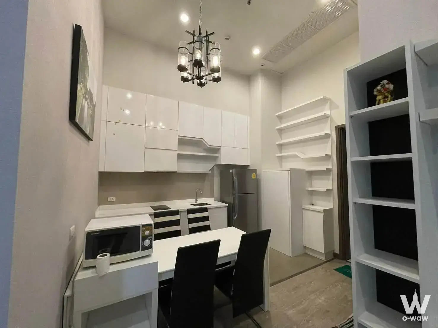 Kitchen dining area in a 2-bed PYNE by Sansiri condo with white cabinets and black induction cooktop