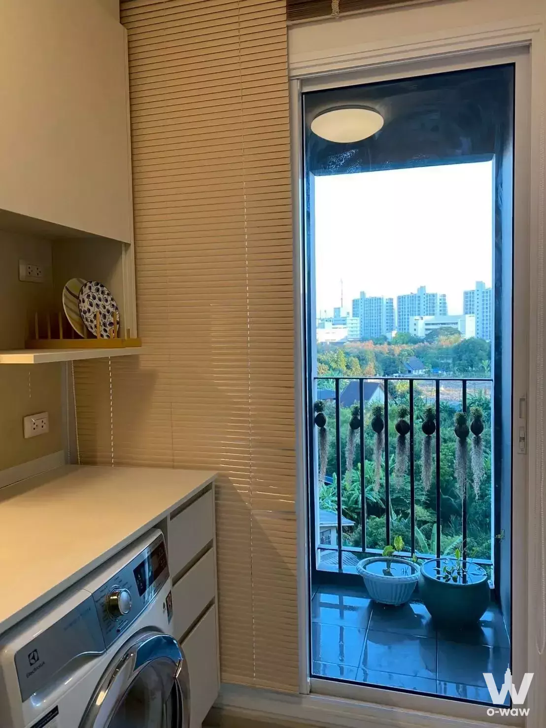 Laundry area in Chapter One Eco Ratchada-HuaiKhwang condo with washing machine and balcony view of green trees