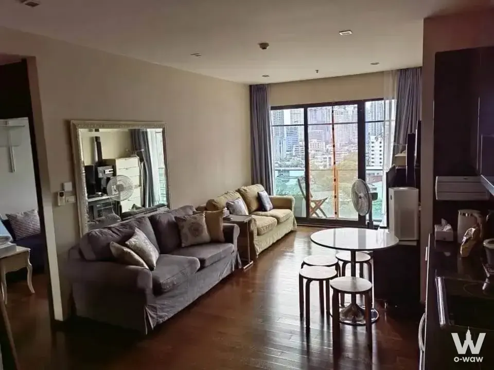 2-bed condo for sale in Noble Remix featuring dark wood floors and city skyline views from the balcony