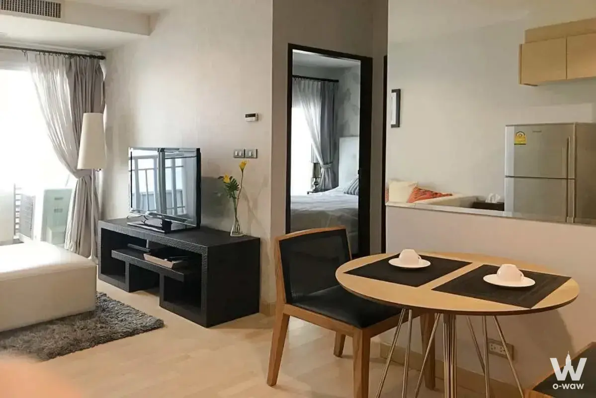 Open-plan living room with light wood floors, white sofa, and dining set in 1-bed townhouse for sale at 59 Heritage
