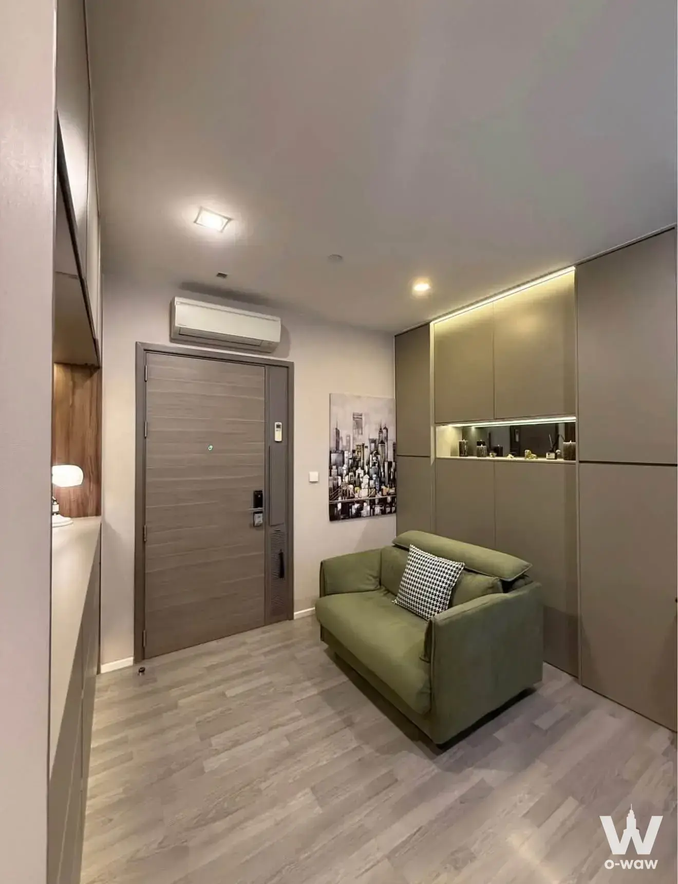 Furnished living room in The Room Sukhumvit 69 featuring olive-green sofa and taupe built-in cabinetry