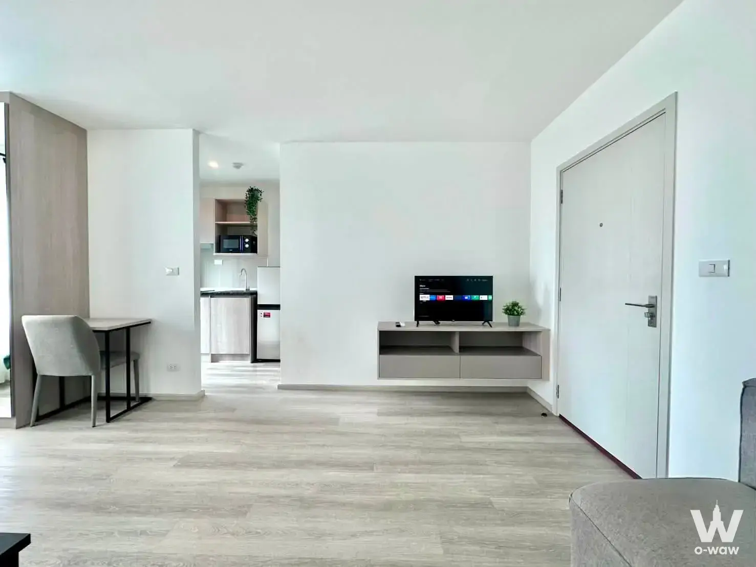 Elio Sathorn-Wutthakat studio interior showing a floating media console, dining nook, and compact kitchenette area