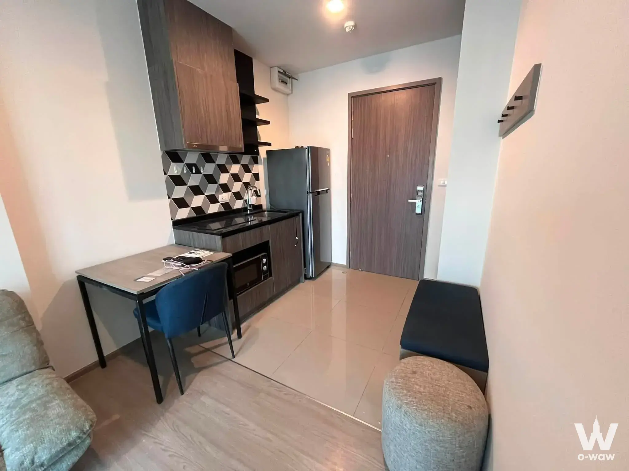 Compact studio kitchenette with dark wood cabinets and geometric tile backsplash in Phetchaburi-Thonglor