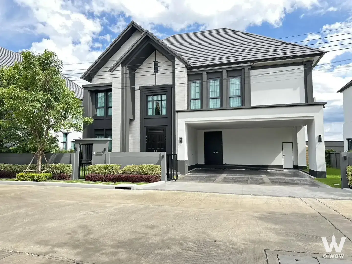Modern two-story house exterior with white stucco walls, dark grey roof, and open-air carport for sale in The City Ramintra