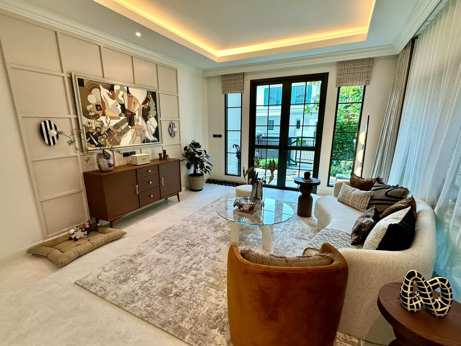 Modern living room with curved sofa, mustard armchair, and wood accents in 4-bed house for sale Setthasiri Ngamwongwan