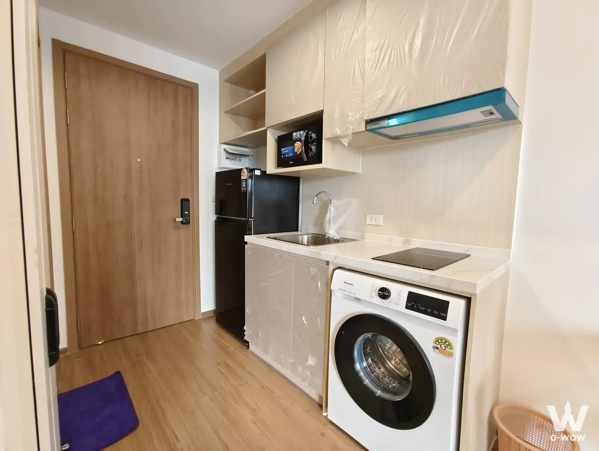 New kitchenette in The Livin Ramkhamhaeng condo with cream cabinetry and integrated washing machine