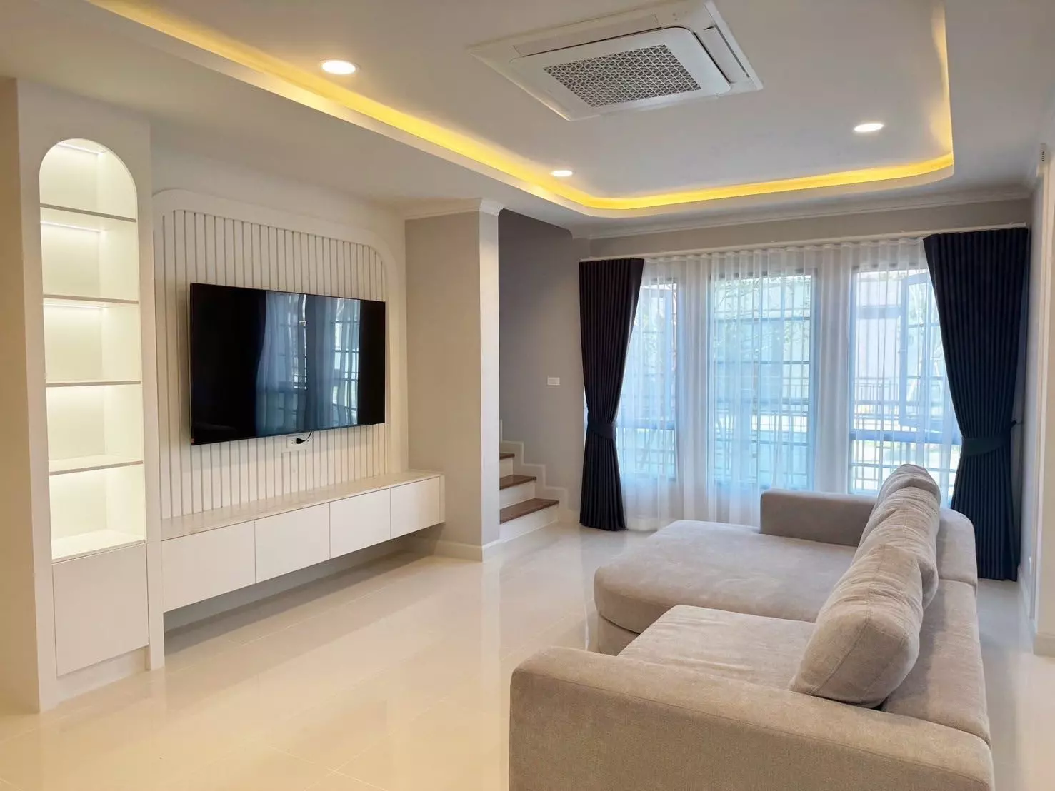 Spacious living room with beige sectional and navy drapes in Centro Bangna 4-bed house