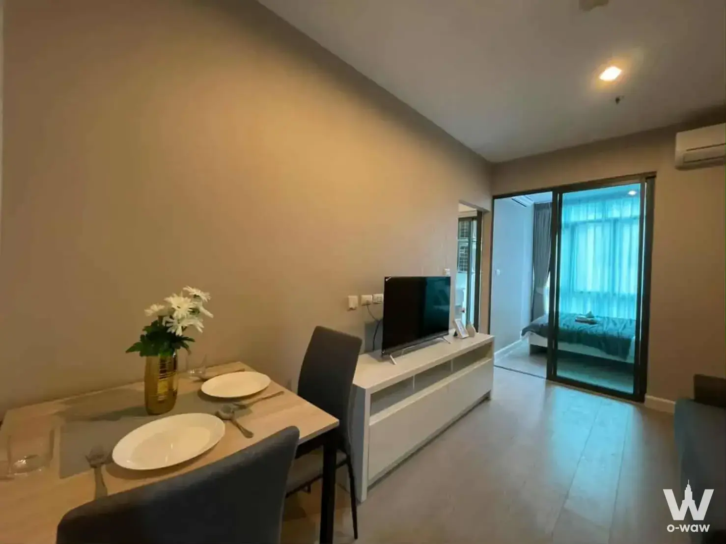1-bed condo for sale in Metro Sky Prachachuen with open-plan living area, light wood flooring, and minimalist beige decor
