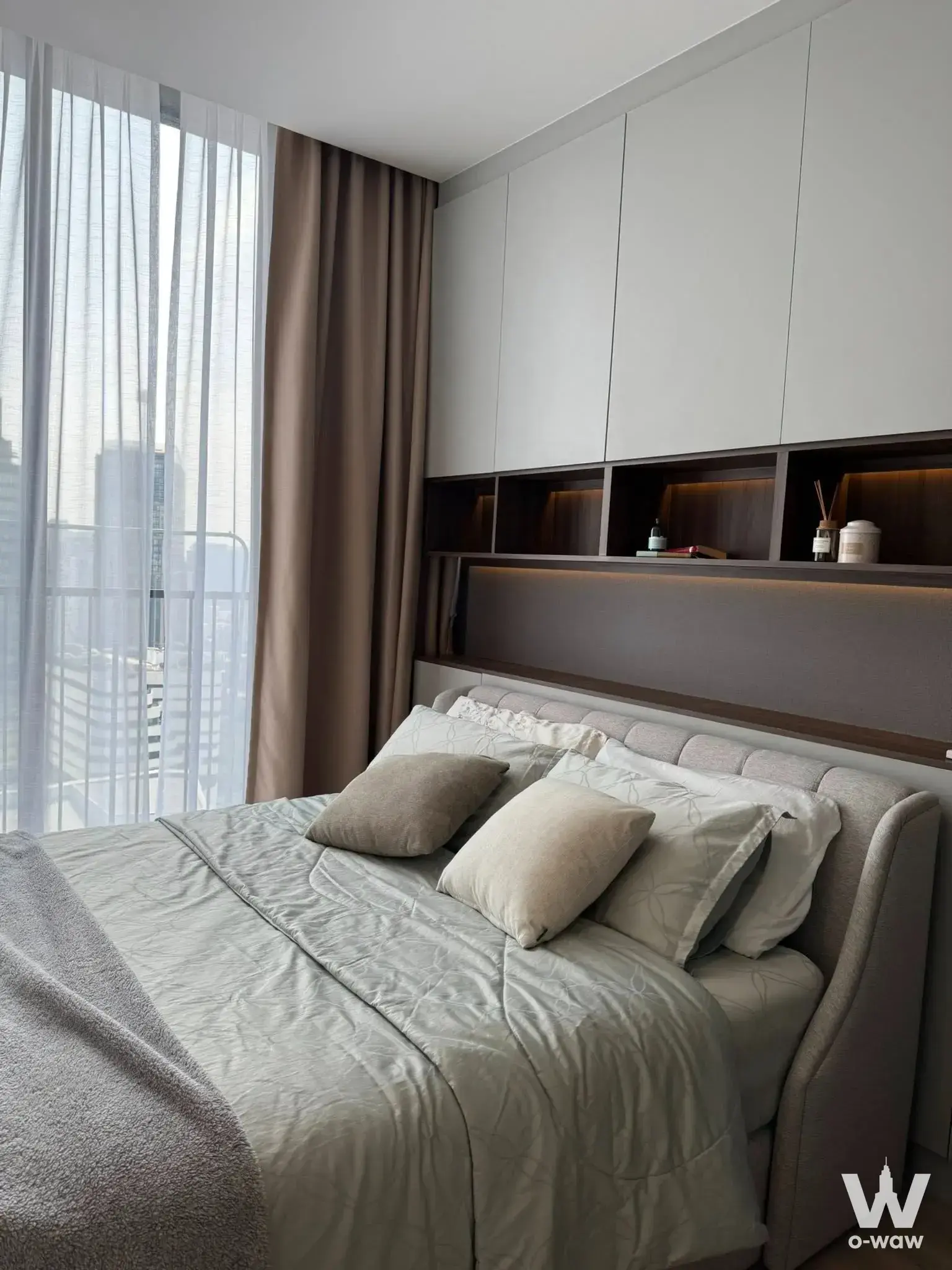 Master bedroom in Noble State 39 condo with walnut shelving and city skyline view