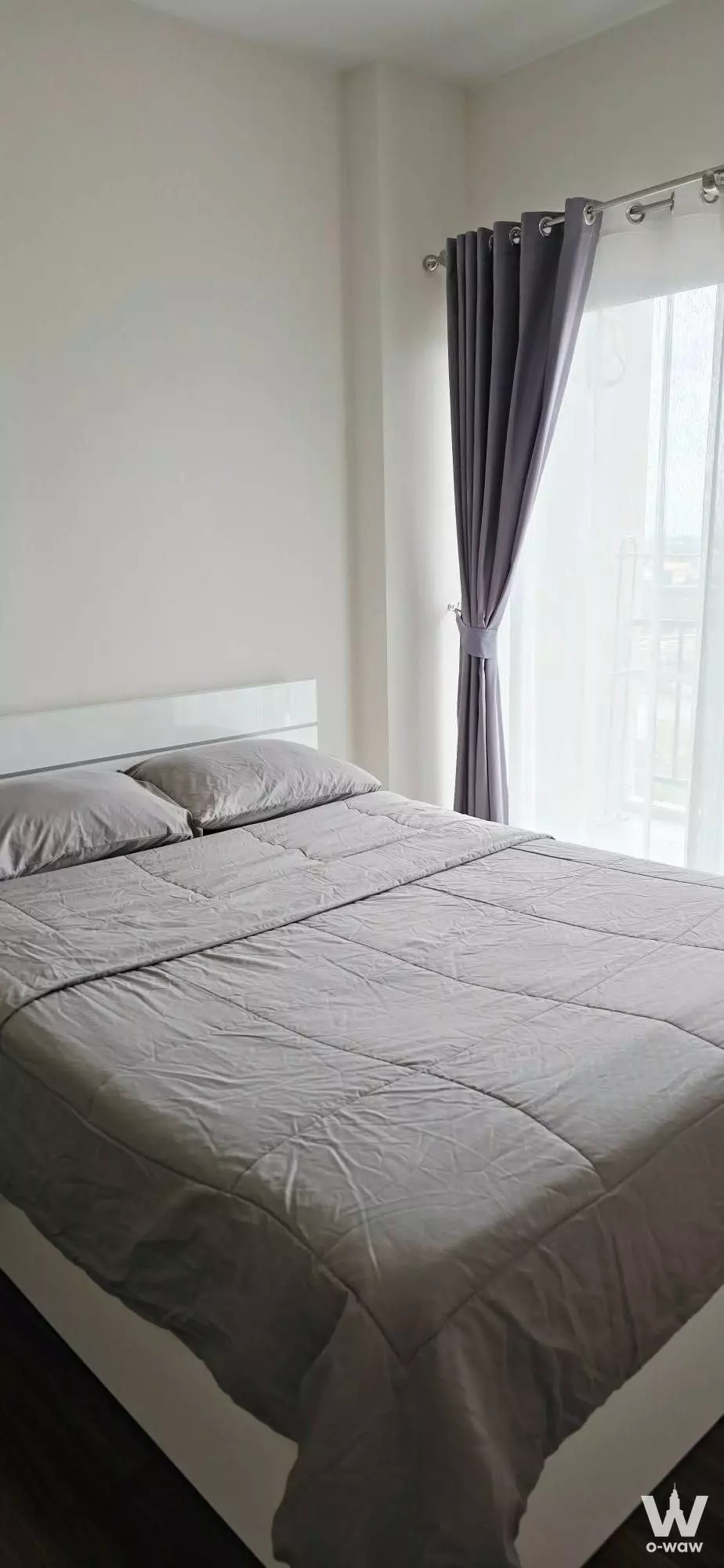 Modern bedroom in Supalai Monte II Chiangmai condo with white bed, dark wood floors, and sheer curtains