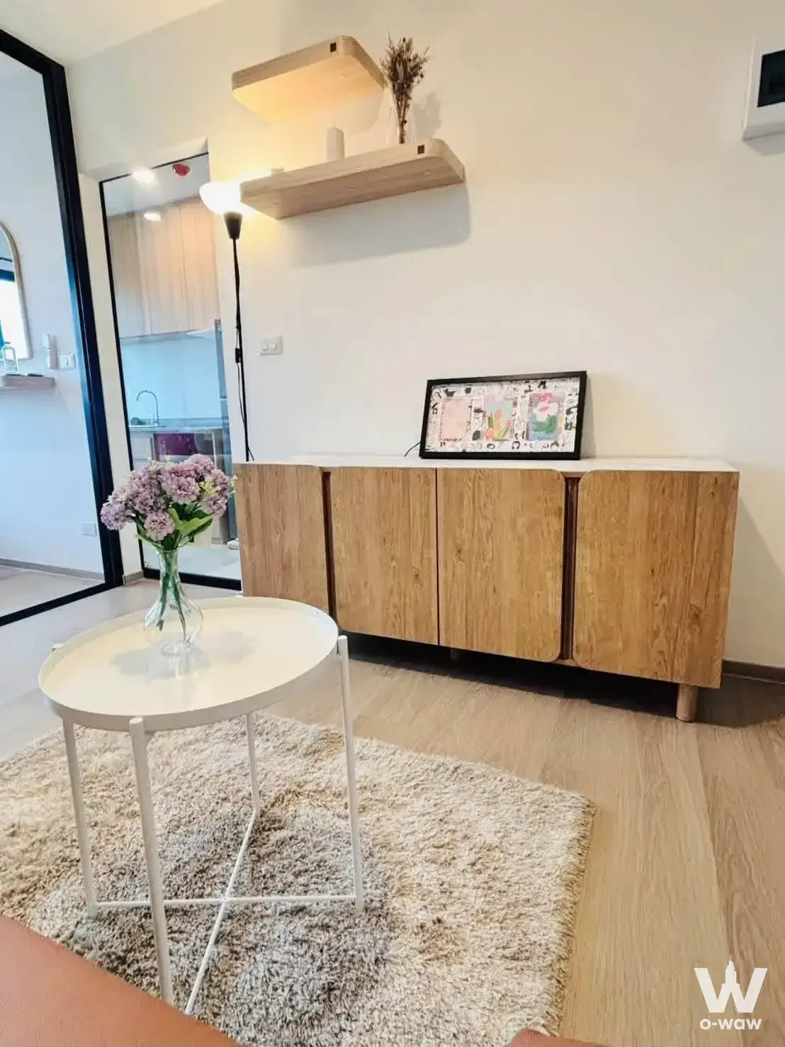 Bright living room corner in The Origin Bangkae with mid-century sideboard, round table, and purple hydrangeas