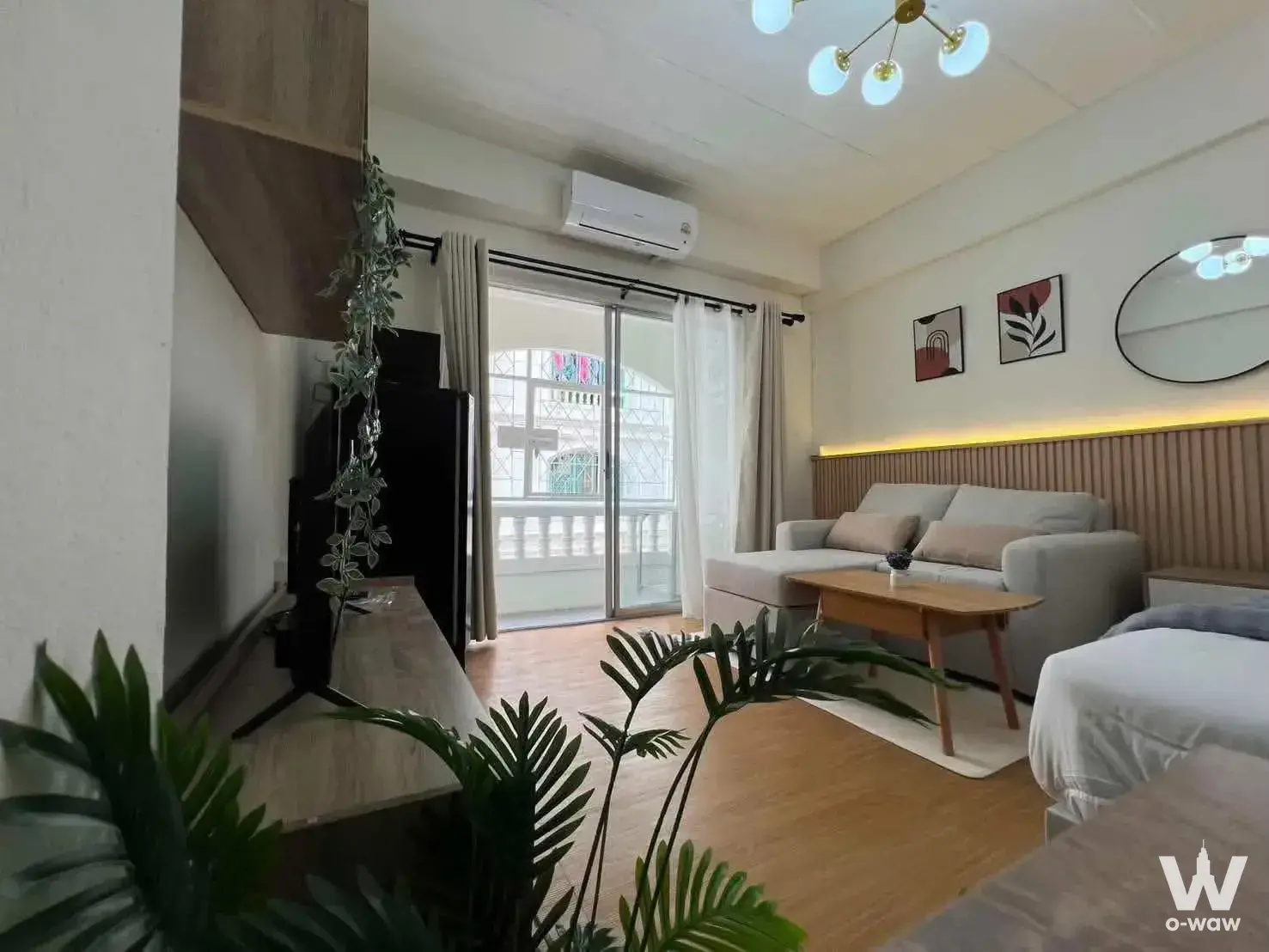 Compact studio in Niran Residence 3 Village with L-shaped sofa, wood feature wall, and balcony access