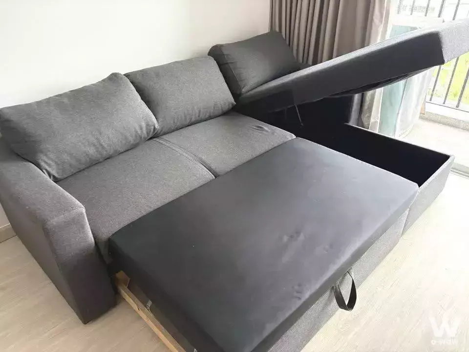 Living room with grey sectional sofa featuring open storage ottoman and floor-to-ceiling windows in Grene Chaengwattana