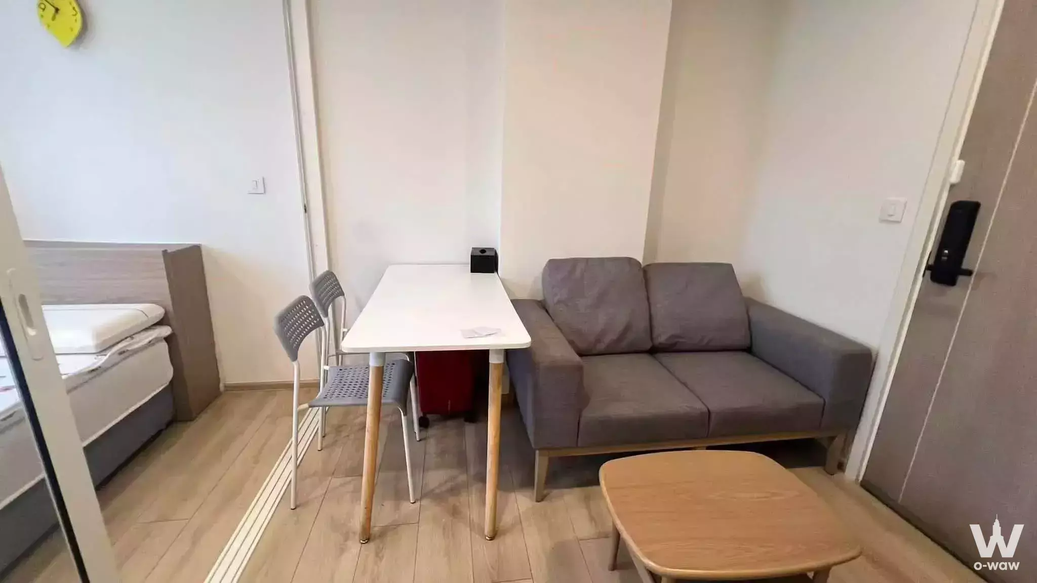 Compact studio with wood floors, grey sofa, and smart lock door in TC Green Building A 1-bed condo for rent