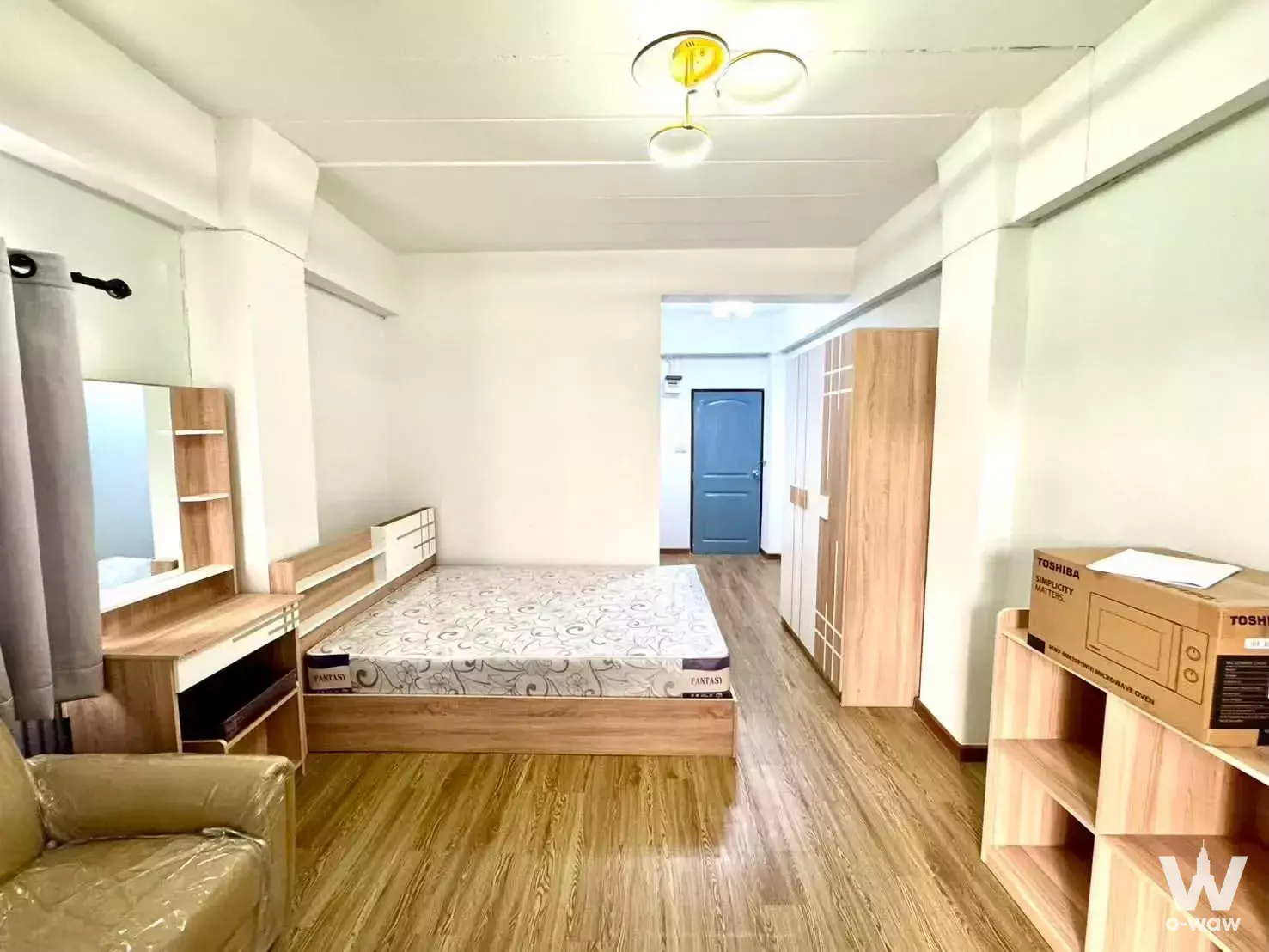 Fully furnished bedroom in Niran Residence 3 Village condo with wood flooring, queen bed, and built-in vanity