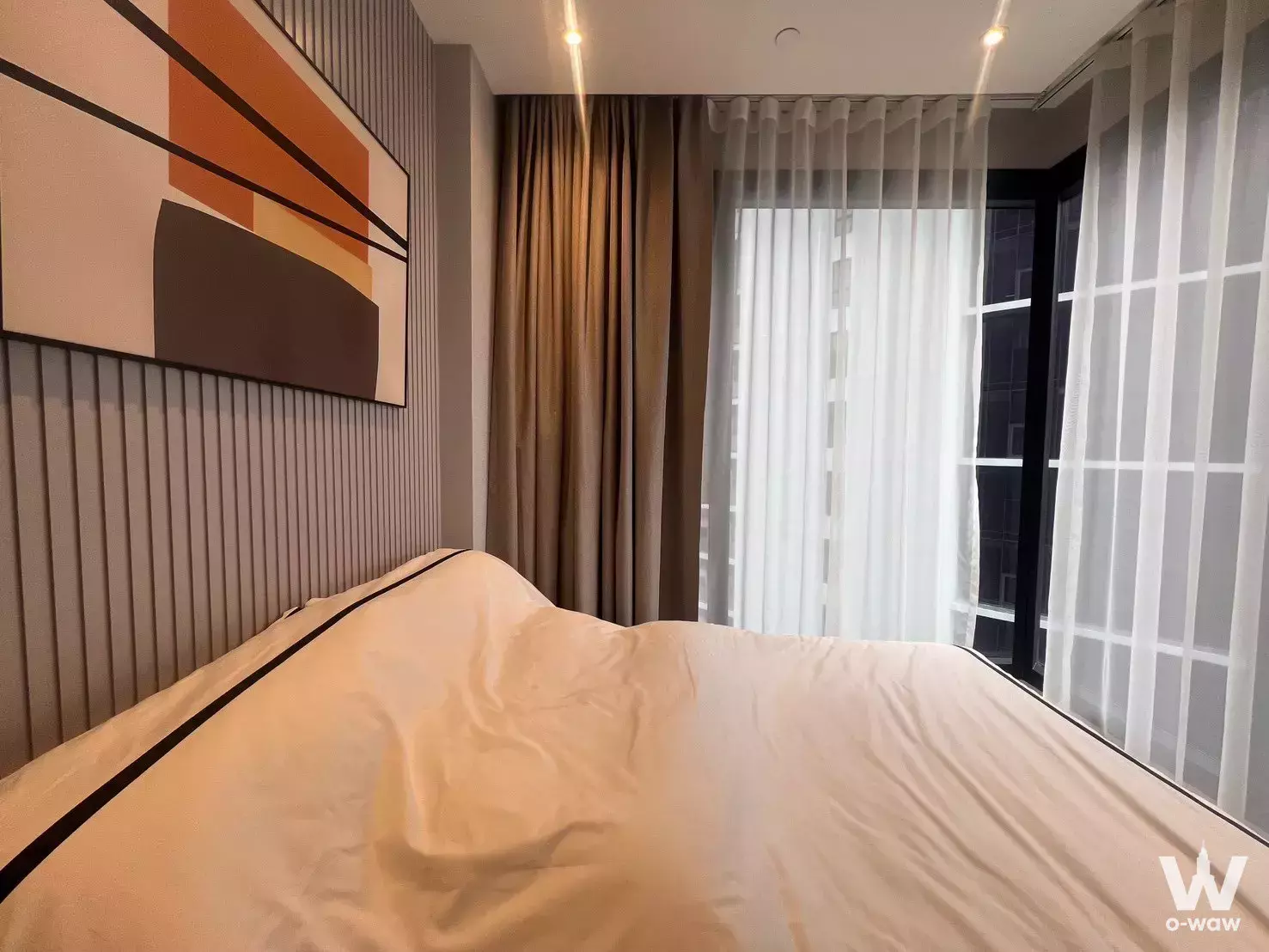 Bedroom with grey fluted wall paneling and abstract art in ASHTON Asoke - Rama 9 condo