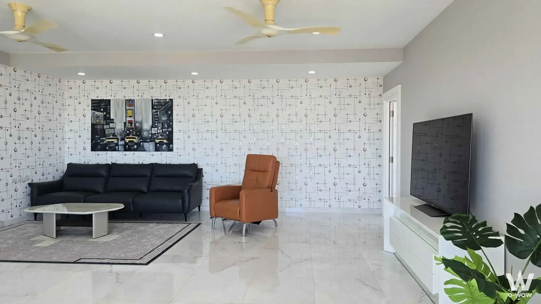 Modern living room in Atmoz Tropicana Bangna condo featuring black leather sofa, geometric wallpaper, and marble floors