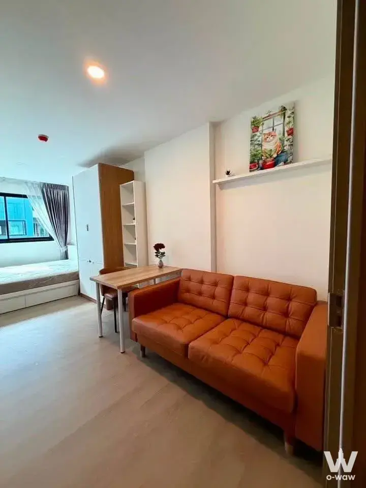 Open-plan studio in The Origin Bangkae with burnt-orange sofa, built-in platform bed, and light wood laminate flooring