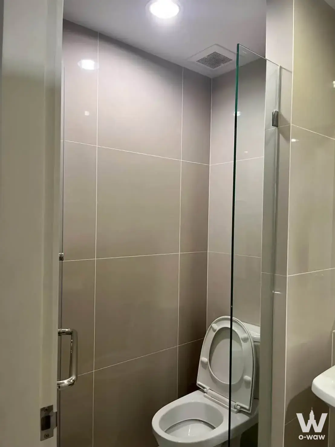 Bathroom in Niche MONO condo with glossy beige tiles and glass shower partition