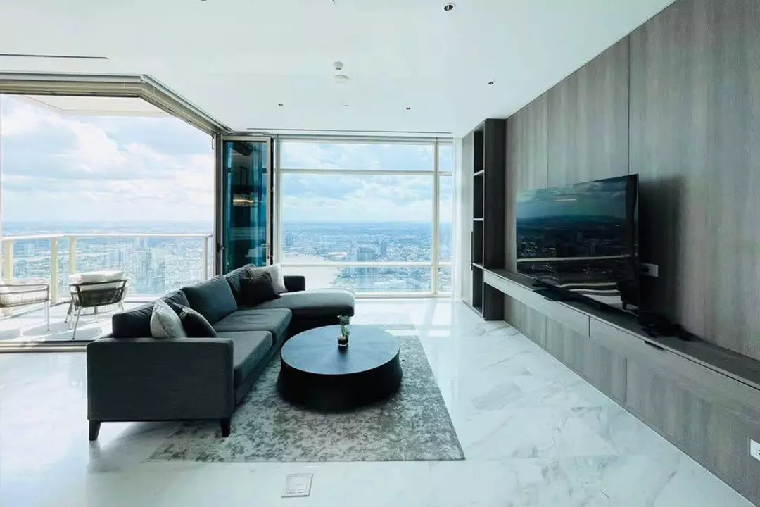 Spacious Four Seasons condo living room with L-shaped sofa, marble floors, and city views