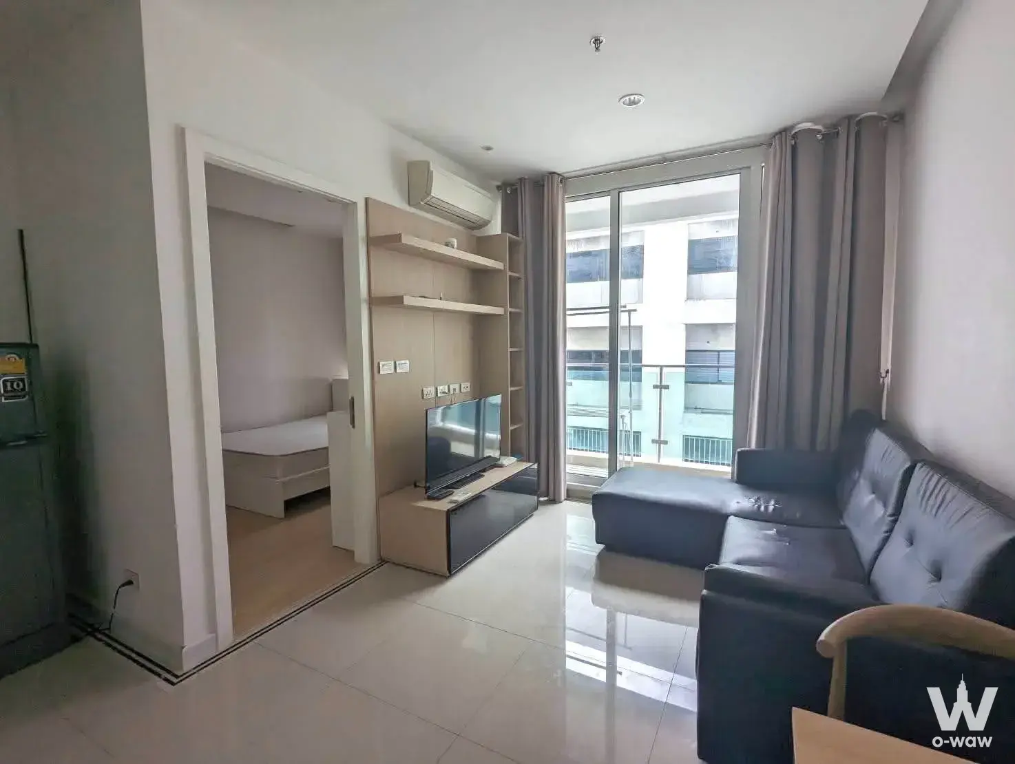 Modern living room in TC Green Rama 9 condo with grey sofa and balcony view