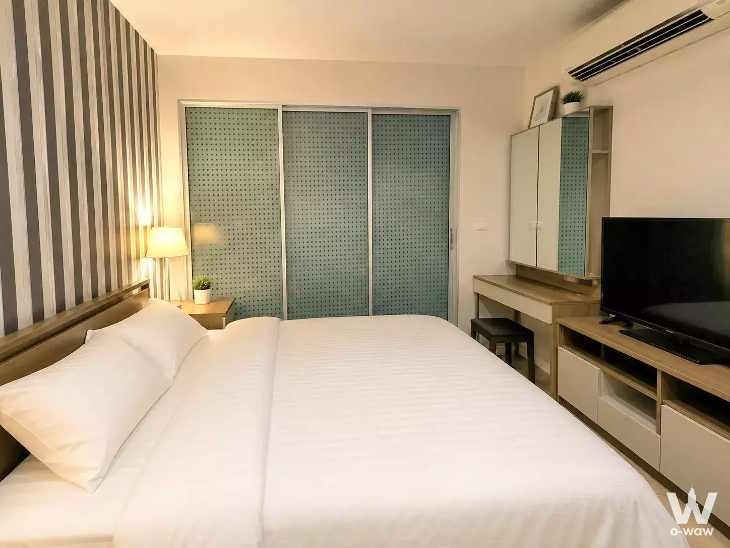 Modern bedroom in RHYTHM Sathorn condo with striped wall, blue-green wardrobe, and built-in desk