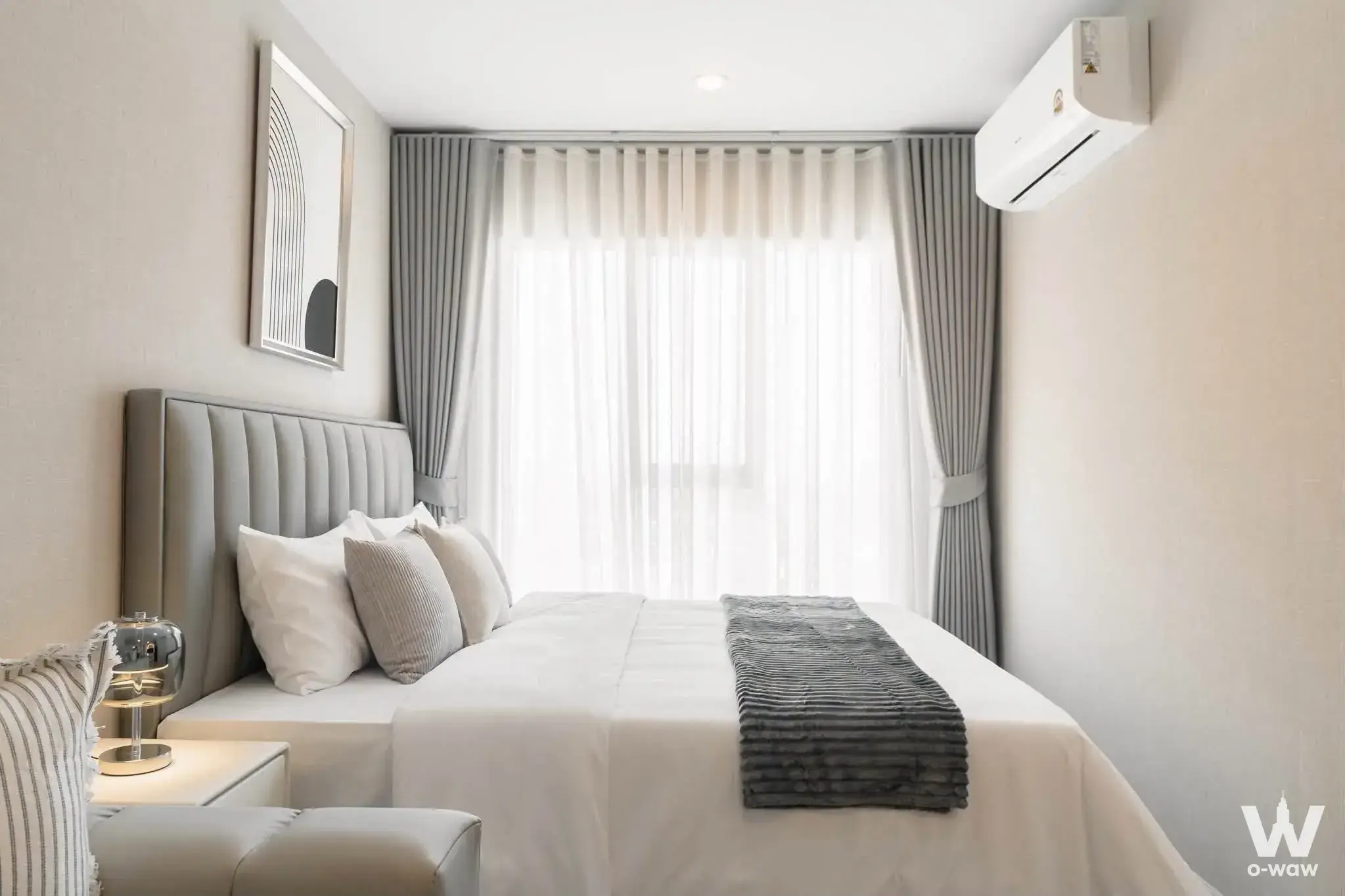 Minimalist bedroom with tufted grey headboard, white linens, and floor-to-ceiling windows