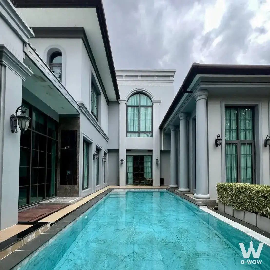 Luxury villa exterior featuring turquoise pool and classical columns at The Grand Pinklao