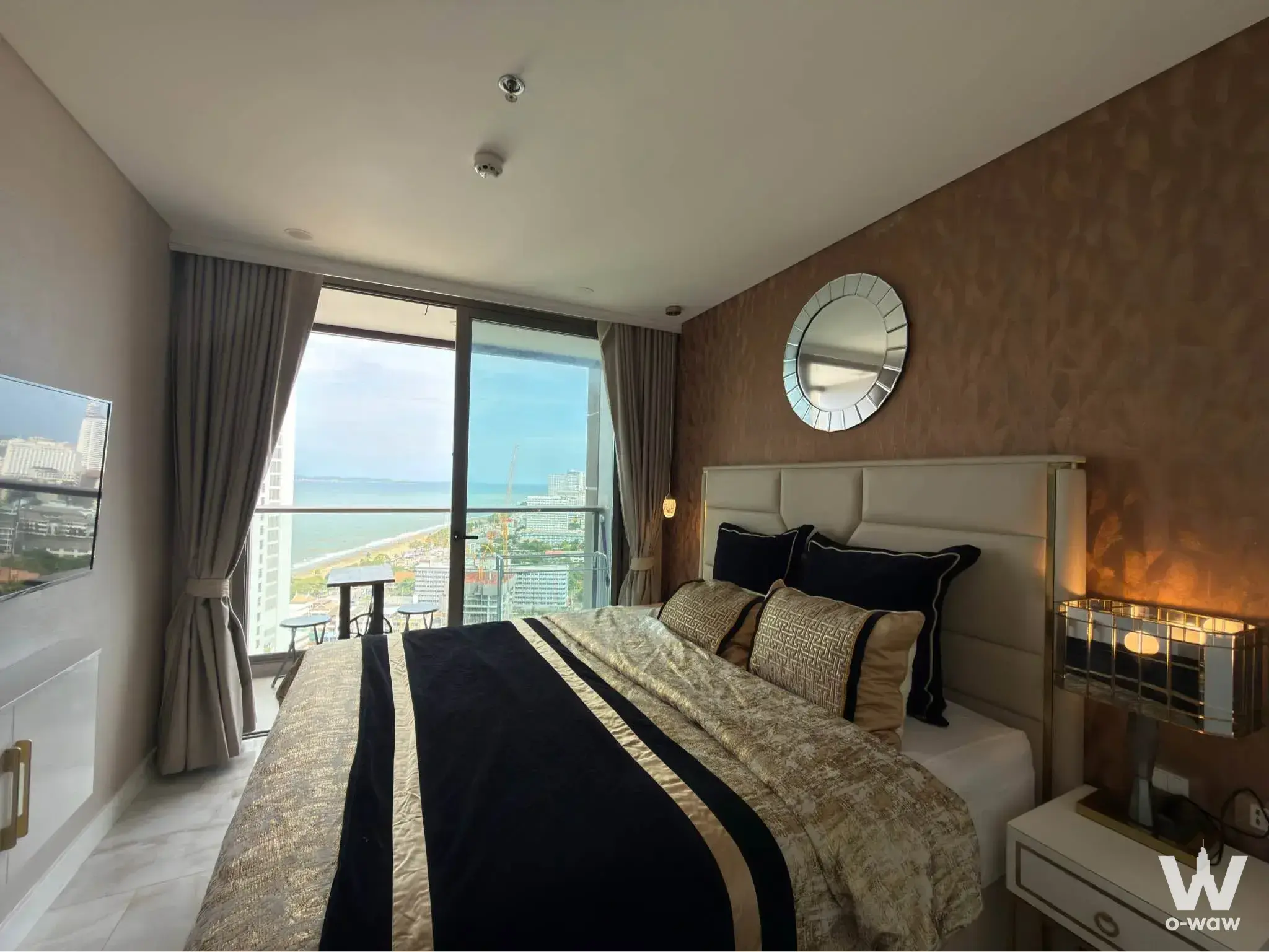 King bed with gold duvet and leather headboard in this Copacabana Coral Reef condo bedroom