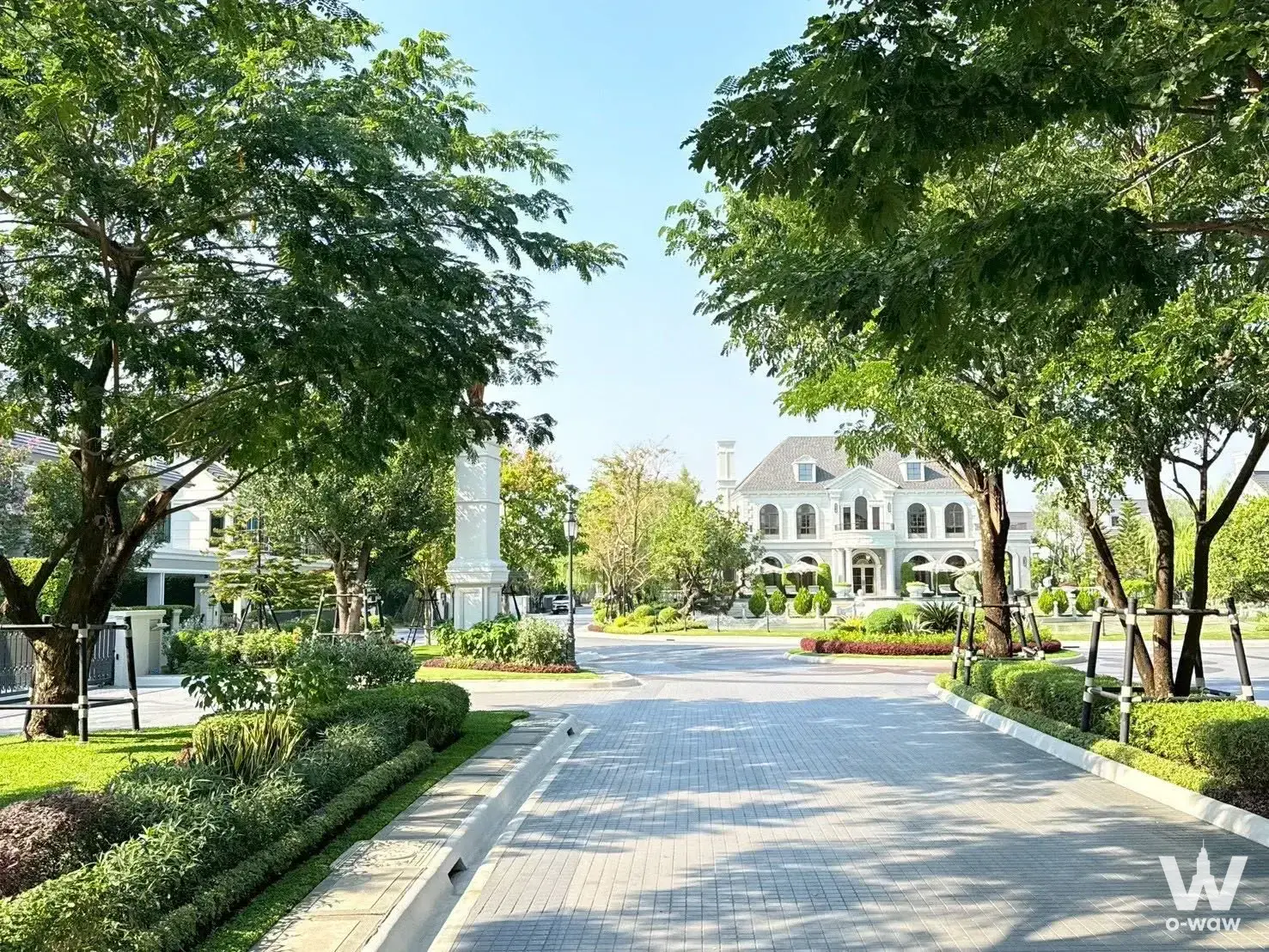 Paved driveway lined with trees leading to a white mansion-style building at Narasiri Krungthep Kreetha 5-bed house for sale