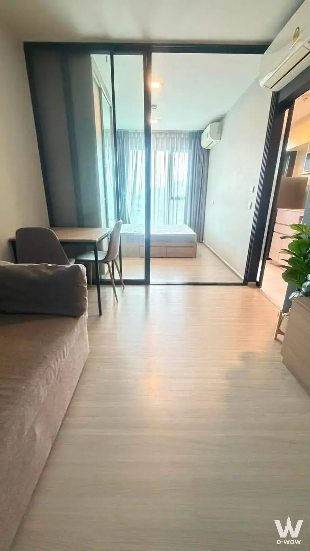 Living room with glass partition in The Privacy S101 condo showing bedroom and kitchenette